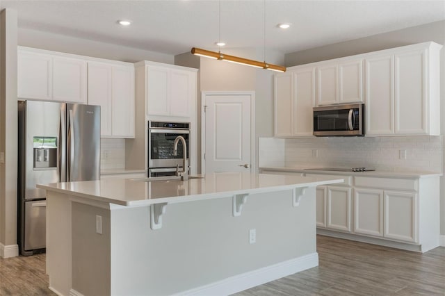 1740 Standing Rock Cir, Oakland, FL 34787 - kitchen featuring stainless steel appliances, an island with sink, light wood finished floors, decorative backsplash, and recessed lighting