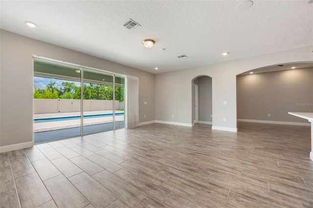 1740 Standing Rock Cir, Oakland, FL 34787 - unfurnished room featuring arched walkways, a textured ceiling, recessed lighting, and wood finished floors