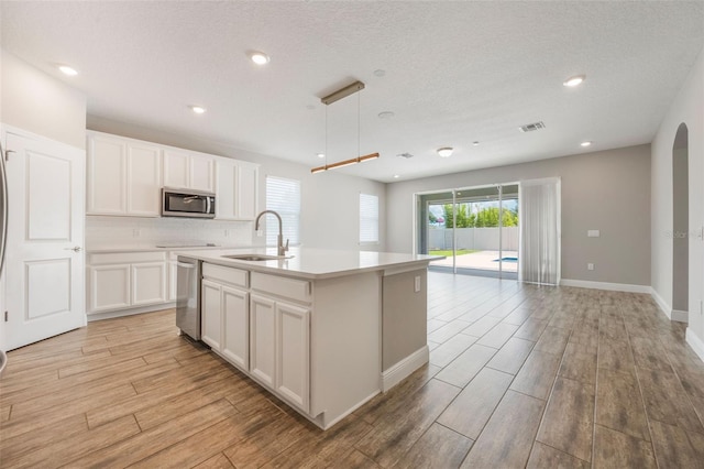 1740 Standing Rock Cir, Oakland, FL 34787 - kitchen featuring appliances with stainless steel finishes, light wood-style flooring, decorative backsplash, an island with sink, and white cabinetry