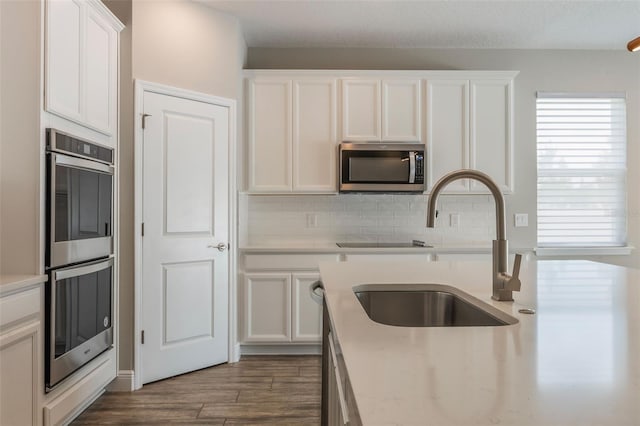 1740 Standing Rock Cir, Oakland, FL 34787 - kitchen with appliances with stainless steel finishes, white cabinets, light countertops, and tasteful backsplash