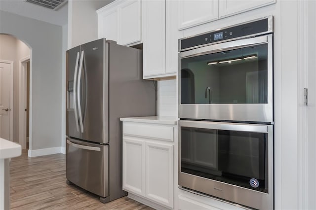 1740 Standing Rock Cir, Oakland, FL 34787 - kitchen with appliances with stainless steel finishes, white cabinets, light wood finished floors, and arched walkways