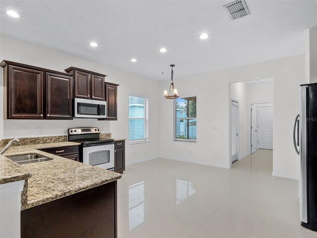 15647 Braintree Ln, Winter Garden, FL 34787 - kitchen with stainless steel appliances, dark brown cabinetry, light stone counters, a chandelier, and recessed lighting