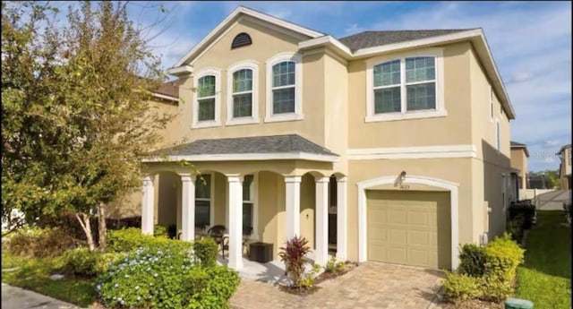 1625 Nassau Point Trl, Kissimmee, FL 34747 - view of front of property with a garage, stucco siding, driveway, and covered porch
