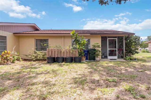 4549 Tippecanoe Trl Unit 20, Sarasota, FL 34233 - rear view of property with stucco siding, a sunroom, and a lawn