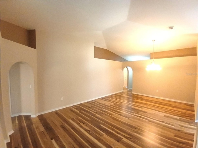 2555 Palmetto Ridge Cir, Apopka, FL 32712 - empty room featuring arched walkways, wood finished floors, and vaulted ceiling