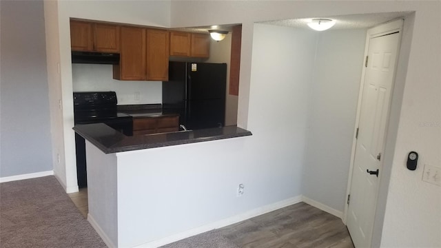 5160 Conroy Rd Unit 1437, Orlando, FL 32811 - kitchen featuring black appliances, exhaust hood, dark countertops, brown cabinetry, and a peninsula