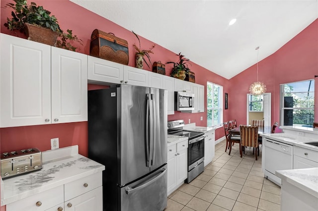 8113 Sun Palm Dr, Kissimmee, FL 34747 - kitchen with stainless steel appliances, lofted ceiling, white cabinets, light tile patterned floors, and hanging light fixtures