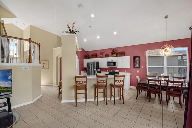 8113 Sun Palm Dr, Kissimmee, FL 34747 - kitchen with stainless steel appliances, vaulted ceiling, a kitchen bar, light countertops, and white cabinetry