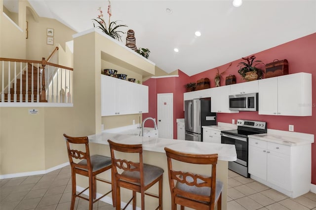 8113 Sun Palm Dr, Kissimmee, FL 34747 - kitchen with appliances with stainless steel finishes, vaulted ceiling, light tile patterned floors, a kitchen breakfast bar, and a peninsula