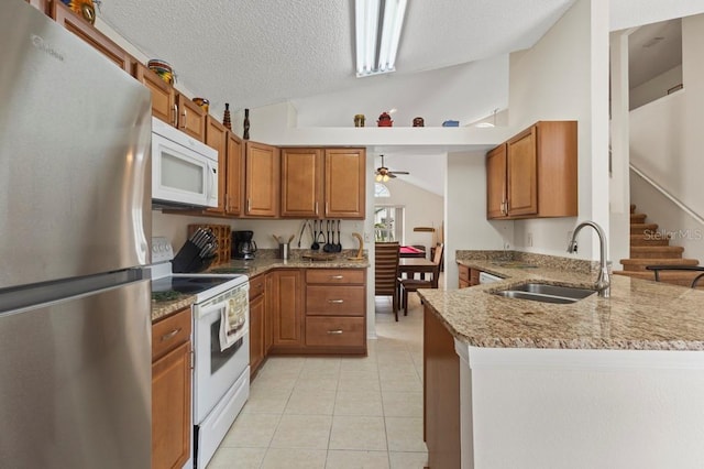 3018 Bransbury Ct, Kissimmee, FL 34747 - kitchen featuring white appliances, a sink, a peninsula, brown cabinetry, and vaulted ceiling