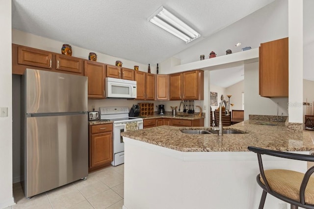 3018 Bransbury Ct, Kissimmee, FL 34747 - kitchen with white appliances, lofted ceiling, a sink, a peninsula, and brown cabinetry