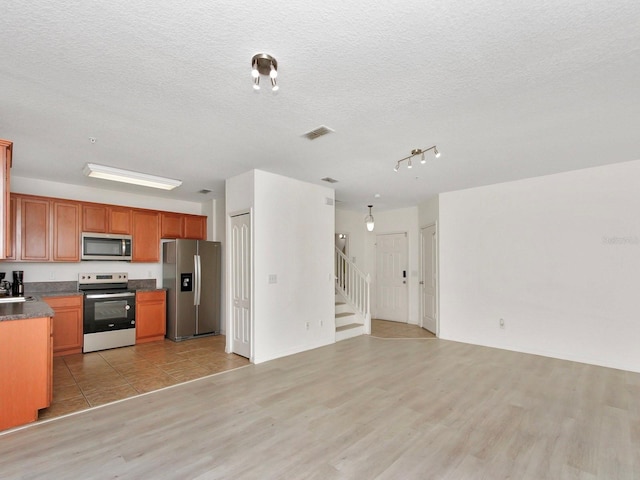 2311 Chatham Place Dr, Orlando, FL 32824 - kitchen with appliances with stainless steel finishes, light wood-style flooring, dark countertops, open floor plan, and brown cabinets