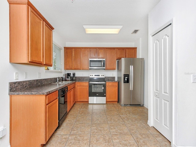 2311 Chatham Place Dr, Orlando, FL 32824 - kitchen with appliances with stainless steel finishes, dark countertops, a sink, brown cabinets, and light tile patterned floors