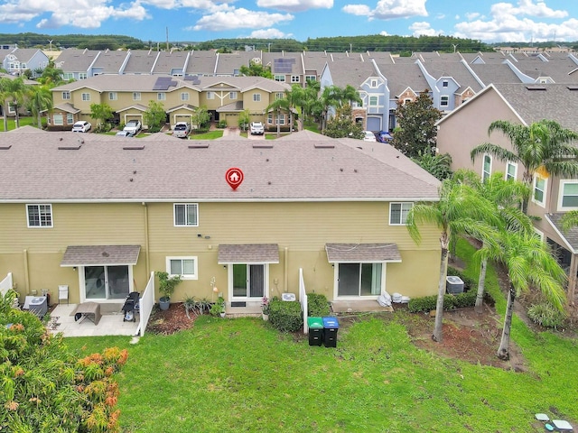 2311 Chatham Place Dr, Orlando, FL 32824 - rear view of property featuring a residential view, a shingled roof, a lawn, a patio area, and stucco siding