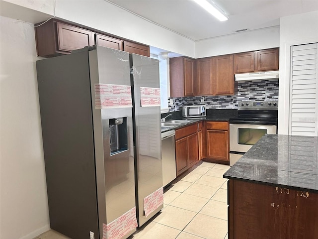 3057 Aaron Burr Ave Unit 2, Winter Park, FL 32792 - kitchen featuring stainless steel appliances, backsplash, under cabinet range hood, light tile patterned floors, and dark stone counters