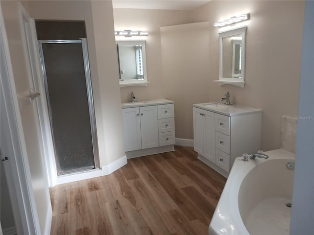 2181 Wekiwa Oaks Dr, Apopka, FL 32703 - full bathroom featuring wood finished floors, a shower stall, two vanities, a bath, and baseboards