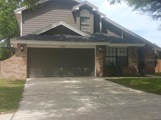 2181 Wekiwa Oaks Dr, Apopka, FL 32703 - view of front of house featuring driveway, brick siding, and roof with shingles