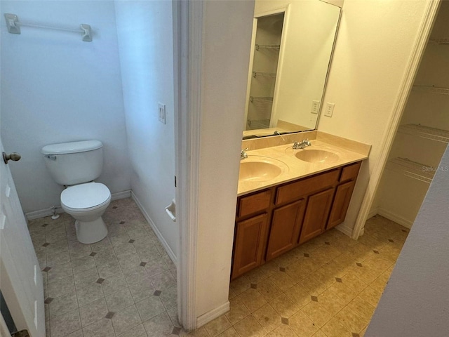 2018 Cypress Bay Blvd, Kissimmee, FL 34743 - bathroom featuring double vanity, a spacious closet, toilet, and baseboards