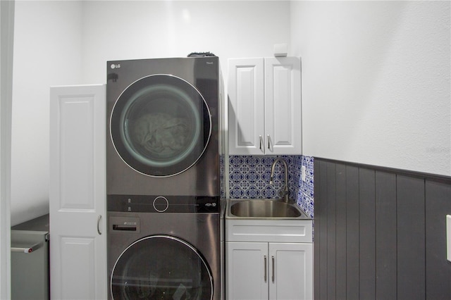 95353 Orchid Blossom Trl, Fernandina Beach, FL 32034 - laundry room featuring stacked washing machine and dryer, cabinet space, and a wainscoted wall