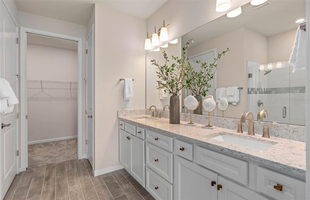 1811 Spring Shower Cir, Kissimmee, FL 34744 - bathroom featuring double vanity, a shower stall, wood tiled floors, a walk in closet, and baseboards