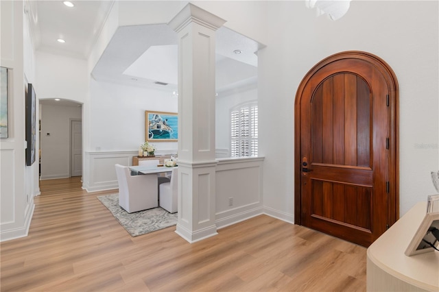 11018 Lake Butler Blvd, Windermere, FL 34786 - entrance foyer featuring decorative columns, arched walkways, light wood finished floors, a decorative wall, and wainscoting