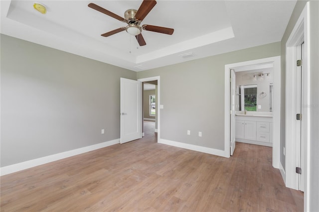 9299 N Tahiti Way, Citrus Springs, FL 34433 - unfurnished bedroom featuring a tray ceiling, light wood-style floors, baseboards, and multiple windows