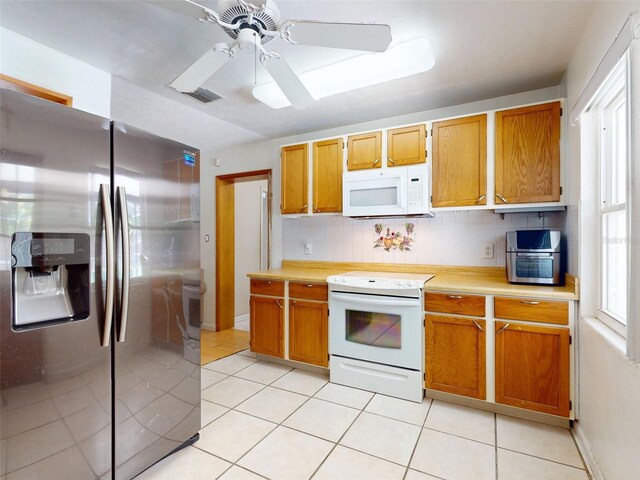 720 Meadow St, Sanford, FL 32773 - kitchen with white appliances, light countertops, light tile patterned floors, a ceiling fan, and brown cabinets