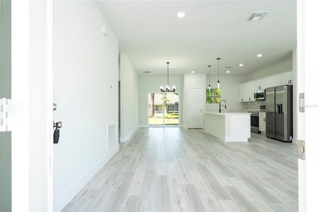 10333 N Halsey Way, Citrus Springs, FL 34434 - kitchen with stainless steel appliances, light countertops, a chandelier, white cabinets, and light wood-style flooring