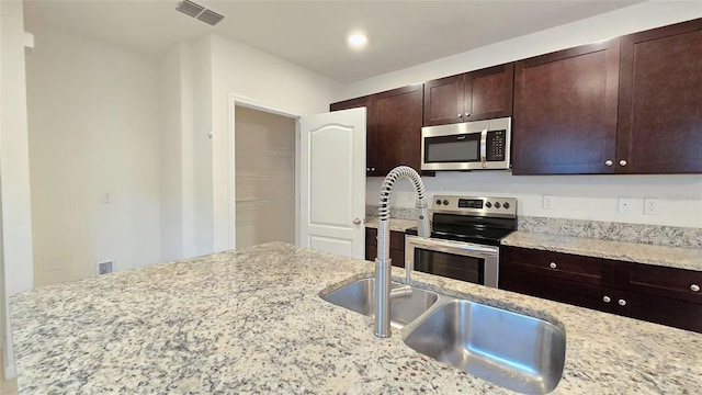 3202 Timber Hawk Cir, Ocoee, FL 34761 - kitchen featuring stainless steel appliances, dark brown cabinetry, and light stone counters