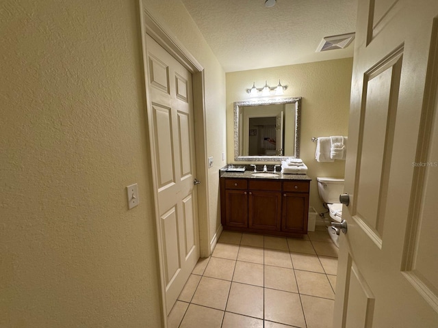 7651 Whisper Way Unit 201, Kissimmee, FL 34747 - half bathroom featuring tile patterned floors, a textured wall, vanity, toilet, and a textured ceiling
