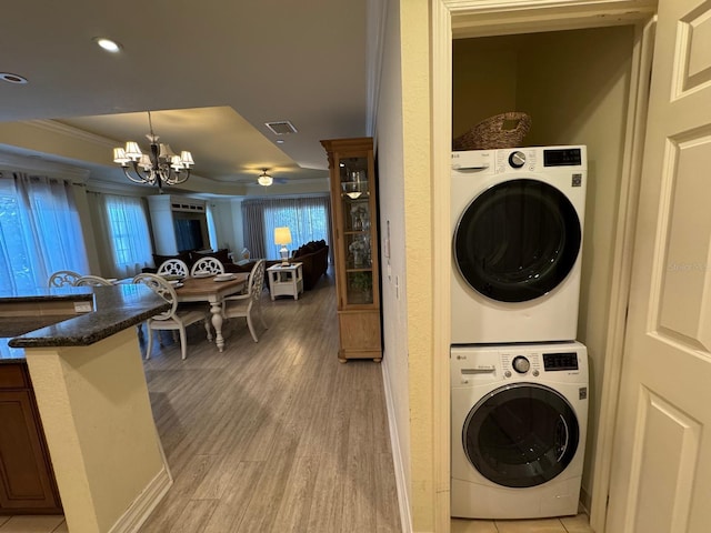 7651 Whisper Way Unit 201, Kissimmee, FL 34747 - laundry area featuring stacked washer / dryer, a chandelier, crown molding, and light wood finished floors