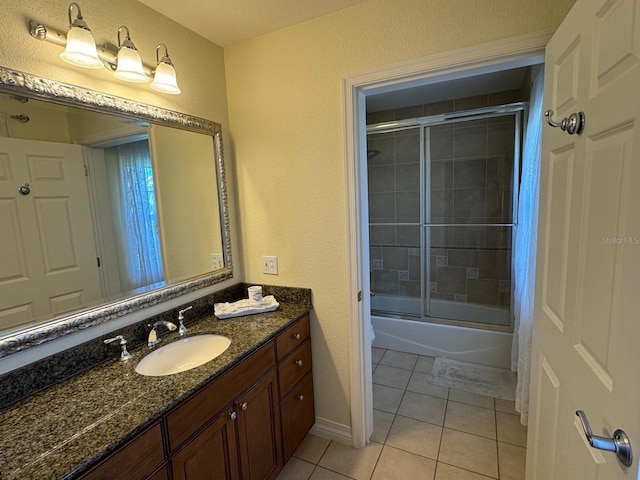 7651 Whisper Way Unit 201, Kissimmee, FL 34747 - full bath featuring tile patterned flooring, vanity, combined bath / shower with glass door, a textured wall, and baseboards