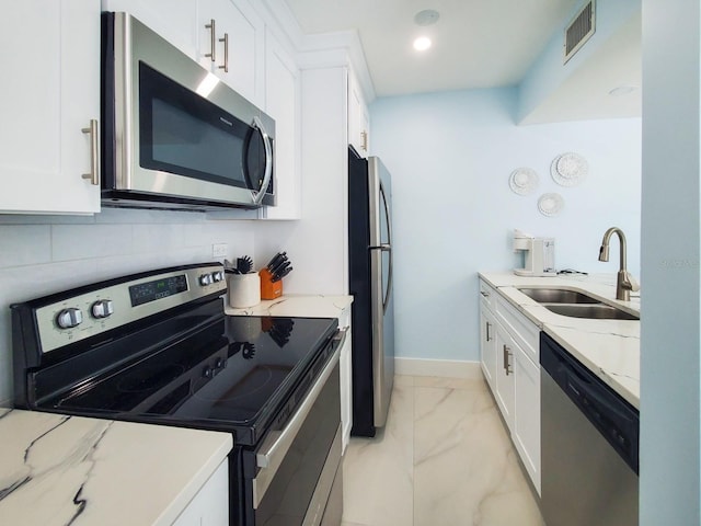 215 Medallion Blvd Unit G, Madeira Beach, FL 33708 - kitchen featuring stainless steel appliances, a sink, light marble finish floors, light stone countertops, and white cabinets