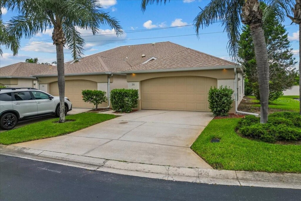206 Islandia Ct Unit U206, Satellite Beach, FL 32937 - view of front of home with an attached garage, driveway, stucco siding, and a shingled roof