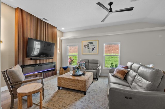1301 Johns Cove Ln, Oakland, FL 34787 - living area featuring wood finished floors, plenty of natural light, a glass covered fireplace, a ceiling fan, and vaulted ceiling