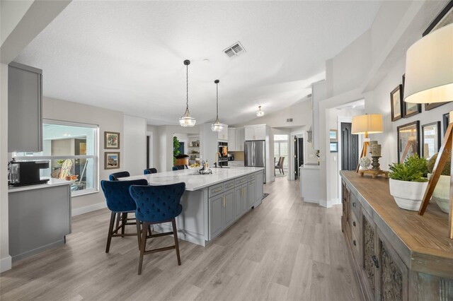 1301 Johns Cove Ln, Oakland, FL 34787 - kitchen featuring gray cabinets, light wood-style floors, a sink, freestanding refrigerator, and lofted ceiling