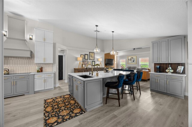 1301 Johns Cove Ln, Oakland, FL 34787 - kitchen featuring a sink, gray cabinets, backsplash, light wood-style flooring, and vaulted ceiling