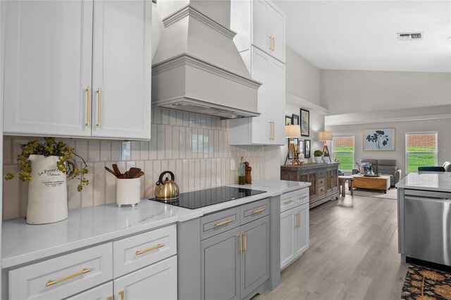 1301 Johns Cove Ln, Oakland, FL 34787 - kitchen with premium range hood, black electric stovetop, stainless steel dishwasher, open floor plan, and decorative backsplash