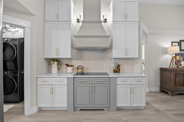 1301 Johns Cove Ln, Oakland, FL 34787 - kitchen featuring black electric stovetop, stacked washer / drying machine, light wood-style flooring, and tasteful backsplash