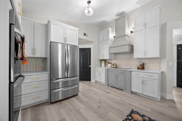 1301 Johns Cove Ln, Oakland, FL 34787 - kitchen with freestanding refrigerator, custom range hood, light countertops, light wood-style flooring, and backsplash