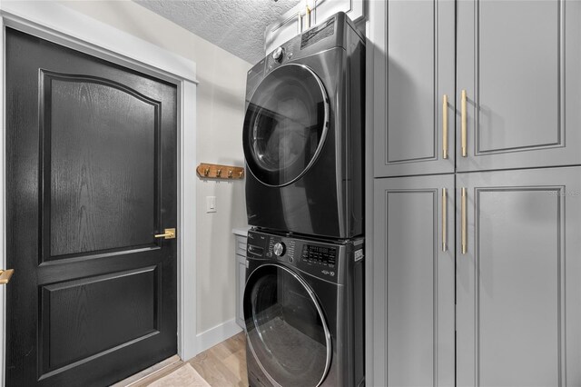1301 Johns Cove Ln, Oakland, FL 34787 - washroom with stacked washing machine and dryer, cabinet space, a textured ceiling, baseboards, and light wood-style floors