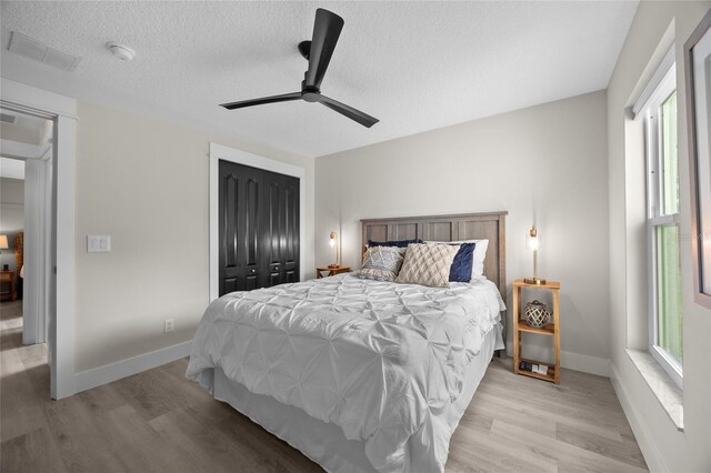 1301 Johns Cove Ln, Oakland, FL 34787 - bedroom featuring multiple windows, light wood-style flooring, a textured ceiling, and a closet