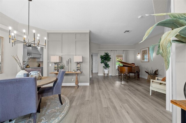 1301 Johns Cove Ln, Oakland, FL 34787 - dining space featuring a chandelier, light wood-style flooring, ornamental molding, baseboards, and a textured ceiling