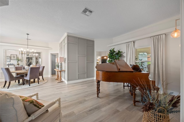 1301 Johns Cove Ln, Oakland, FL 34787 - living room with a textured ceiling, a chandelier, light wood-style floors, and ornamental molding