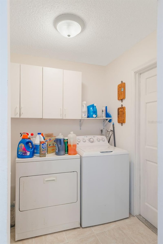 109 Hunter Point Ct, Debary, FL 32713 - laundry area featuring washing machine and dryer, cabinet space, a textured ceiling, and light tile patterned flooring