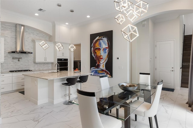 8113 Via Vittoria Way, Orlando, FL 32819 - dining area with light marble finish flooring, ornamental molding, arched walkways, and recessed lighting