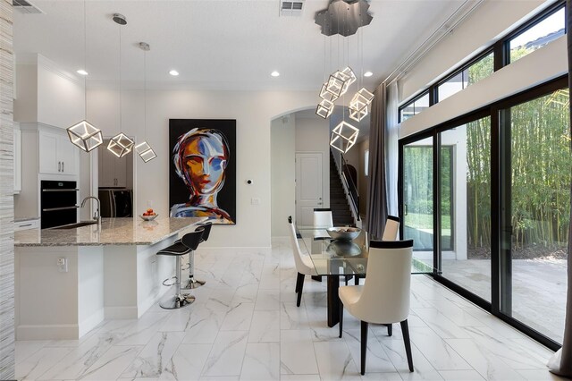 8113 Via Vittoria Way, Orlando, FL 32819 - dining space with light marble finish flooring, baseboards, crown molding, recessed lighting, and arched walkways