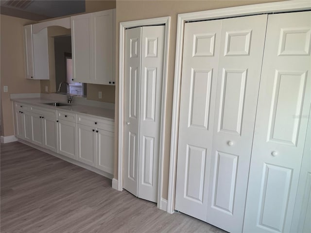 12421 Early Run Ln, Riverview, FL 33578 - kitchen featuring a sink, light wood-style flooring, light countertops, white cabinetry, and baseboards