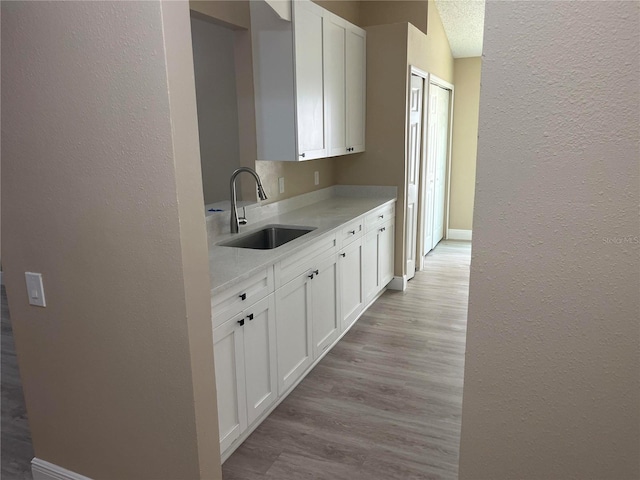 12421 Early Run Ln, Riverview, FL 33578 - kitchen featuring a sink, a textured wall, light wood-type flooring, white cabinets, and light countertops