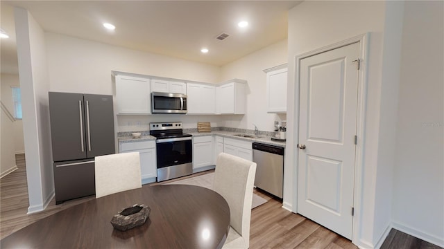 6166 Daerr Ridge St, Zephyrhills, FL 33542 - kitchen with stainless steel appliances, light wood finished floors, white cabinets, a sink, and baseboards